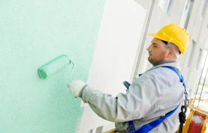 Mężczyzna maluje ścianę na zielono.